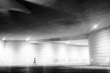 Siyah ve beyaz sanat bir kadın gece şehir merkezindeki galeri manzaralı bir yerde tek başına yürüyor.