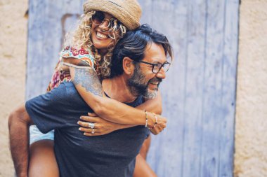 Kaygısız çift dışarıda birlikte vakit geçiriyorlar. Adam, güneş gözlüklü ve hasır şapkalı neşeli, dövmeli kadına sırtına biniyor..