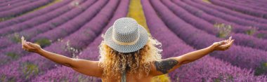 Rear view of beautiful woman standing on lavender flower field with arms outstretched clipart