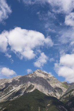 Bulutlu gökyüzüne karşı karla kaplı dağın manzarası.