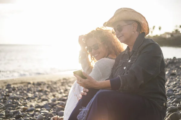 Mujer Mayor Con Hija Pequeña Relajándose Playa Madre Mostrando Teléfono — Foto de Stock