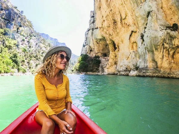 岩の多い山の崖の中の緑の水の峡谷の表面にカヌーで彼女の乗車を楽しんで帽子の幸せな美しい女性 — ストック写真