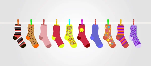 Векторные разноцветные носки на сером фоне висят на веревке — стоковый вектор