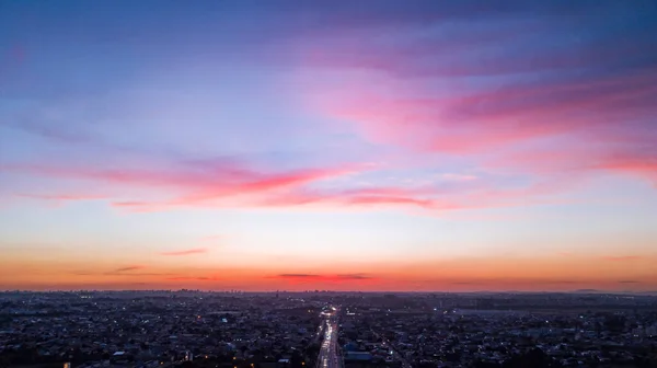 空中无人机图像日落与香草的天空和乌云与粉红色和紫色的颜色 在整个城市的底部 — 图库照片