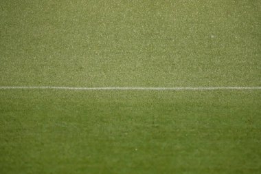 Üzerinde sentetik çimenler olan futbol sahası beyaz bir çizgiyle ıslanıyor.