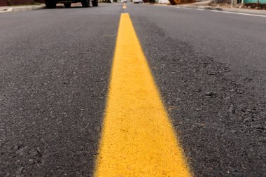 Asfalt izi biraz toprak ve deseniyle yeni yapılmış, görüntünün ortasına ve sokak ufkunun üzerine sarı bir şerit çizilmiş.