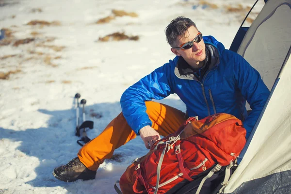 Mann mit Rucksack sitzt in Zeltnähe. — Stockfoto