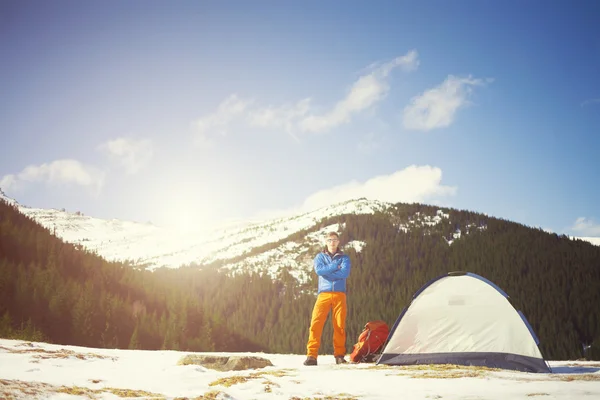 A tourist stands near a tent and a backpack. — Stock Photo, Image