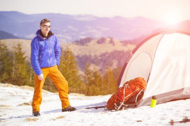 Bir turist bir çadır ve bir sırt çantası duruyor.