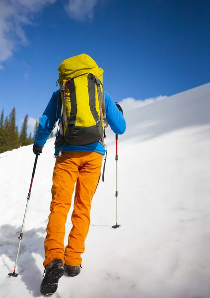 Escalador com uma mochila sobe a neve . — Fotografia de Stock