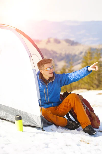 A tourist stands near a tent and a backpack. — Stock Photo, Image