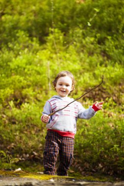 Ormanda oynayan küçük bir çocuk.