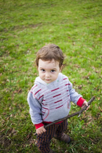 En liten pojke spelar i skogen. — Stockfoto