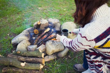 Ateşin yanında oturan insanlar.