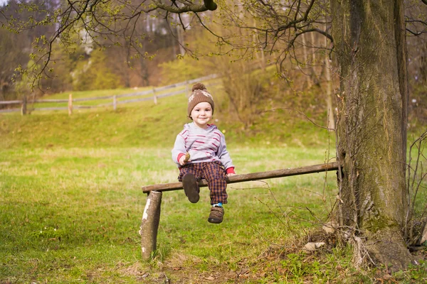 Küçük bir çocuk bir ağacın altında oturuyor. — Stok fotoğraf