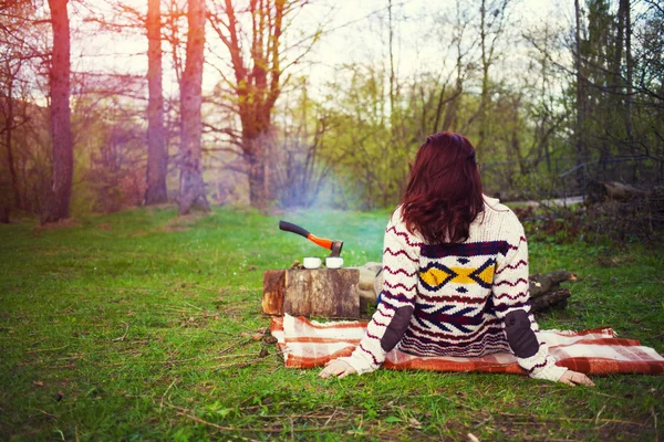 Het meisje in een warme trui zitten bij het haardvuur. — Stockfoto