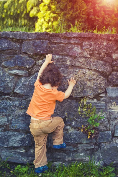 Мальчик перелезает через забор . — стоковое фото