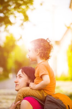 Çocuk annesinin omuzlarına oturuyor.
