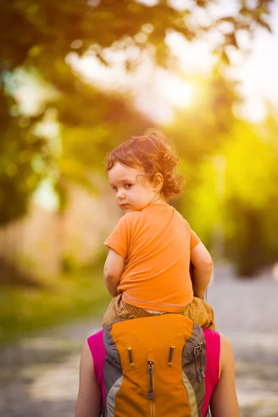 Barnet sitter på mammas axlar. — Stockfoto