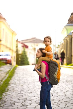 Çocuk annesinin omuzlarına oturuyor.