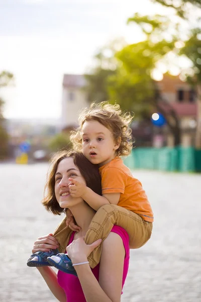 Το παιδί κάθεται πάνω στους ώμους της μαμάς. — Φωτογραφία Αρχείου