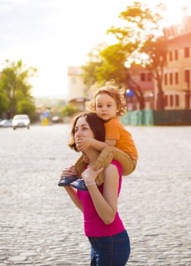 Çocuk annesinin omuzlarına oturuyor.