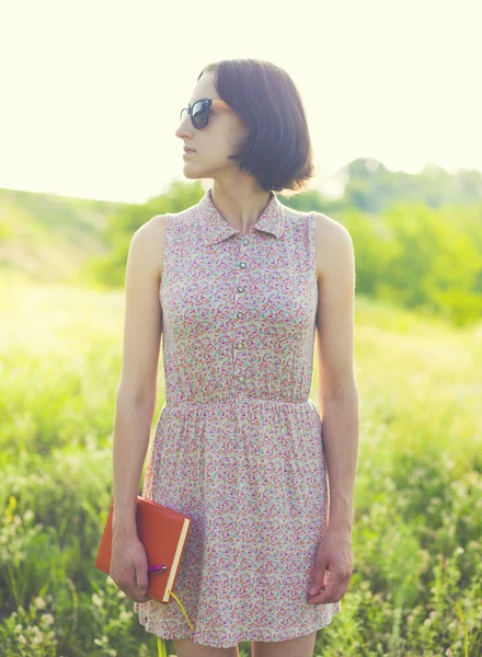 Menina no vestido de verão segurando um livro . — Fotografia de Stock