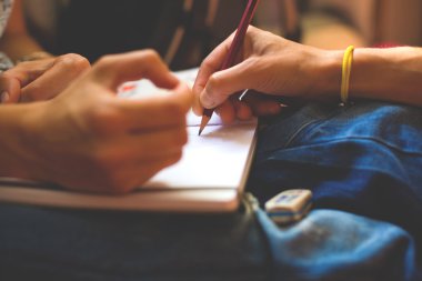 Bir kişi ile bir defter bir kalem çizer.