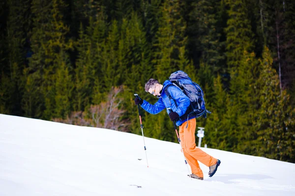 Bergbeklimmer wandelingen op een besneeuwde helling. — Stockfoto