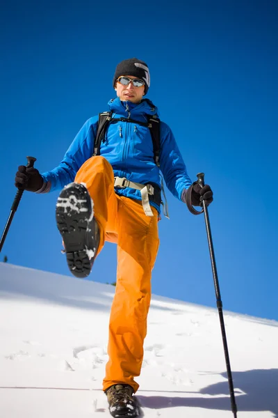 Alpinista de montanha caminha em uma encosta nevada . — Fotografia de Stock