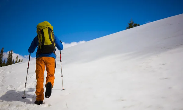 Alpiniste marche sur une pente enneigée . — Photo