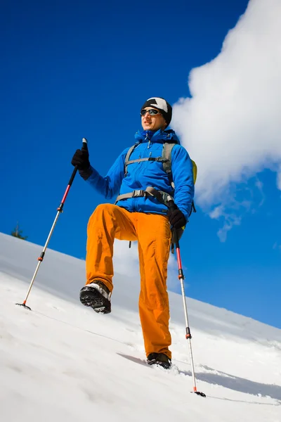 Alpinista de montanha caminha em uma encosta nevada . — Fotografia de Stock