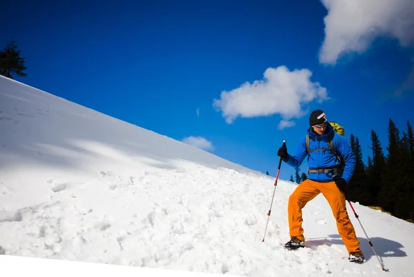 Ορειβάτης βουνών περπατά σε μια χιονισμένη πλαγιά. — Φωτογραφία Αρχείου