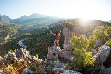 Sırt çantalı bir kadın, elleri havada bir dağın tepesinde durur ve bir vadinin güzelliğine hayran kalır, güzel yerlere seyahat eder, hedefe ulaşır, Türkiye 'nin güzel manzarasına..