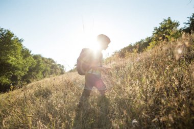 Sırt çantalı bir çocuk çayırda yürüyor, bir çocuk vahşi hayatı keşfediyor, bir çocuk ağaçların arasında tek başına duruyor, bir çocuğun portresi..