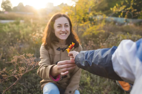 A child gives a flower to his mother, a boy walks with his mom, a woman sniffs a flower, a portrait of a smiling woman.