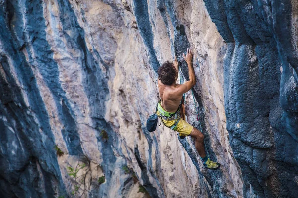 Güçlü bir adam kayaya tırmanır, güçlü sırt kasları, Türkiye 'de kaya tırmanışı, dayanıklılık ve güç eğitimi alır, ekstrem sporlarda çalışan bir adam, dağcı doğada eğitim görür..