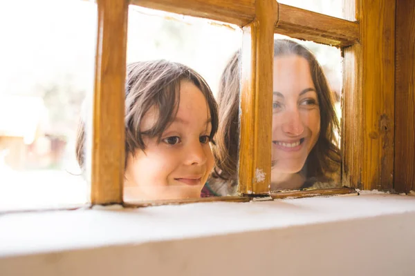 Menino Com Sua Mãe Curiosamente Espreita Pela Janela Uma Casa — Fotografia de Stock