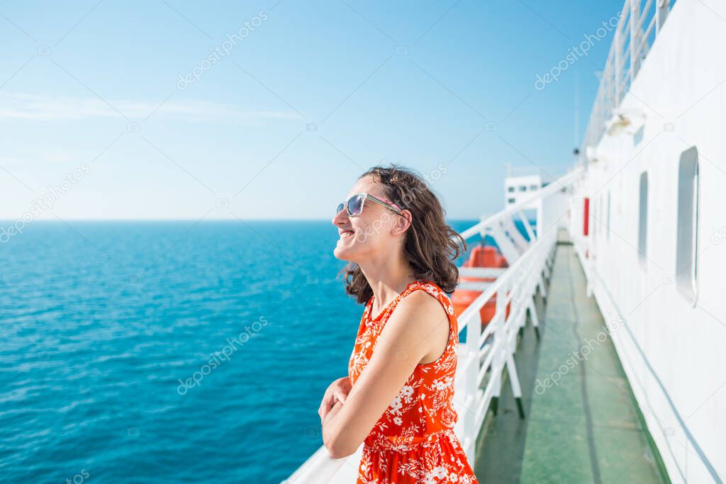 A woman is sailing on a cruise ship, a girl is standing near the fence on a ship and looking at the sea, traveling by ferry, a brunette in a summer dress admires the ocean.