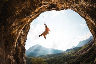 İpe asılı kaya tırmanışçısı, kemer şeklinde bir kayaya tırmanan bir kadın mağaraya tırmanan, ipe tırmanan, Türkiye 'de kaya tırmanışı yapan bir kız. .