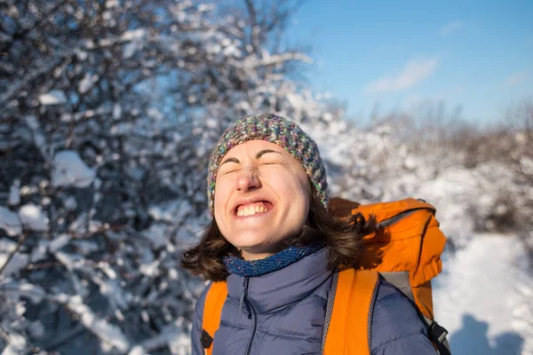 一个戴着针织帽子的女孩的画像 在雪地的森林里 背着背包微笑的女人 一个过冬的女人冬季爬山 — 图库照片