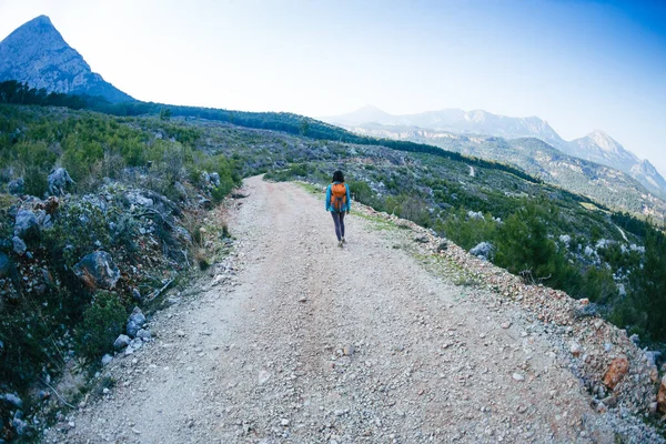 배낭을 여인이 산길을 있는데 아름다운 산등성 배경으로 소녀가 혼자서 여행을 — 스톡 사진