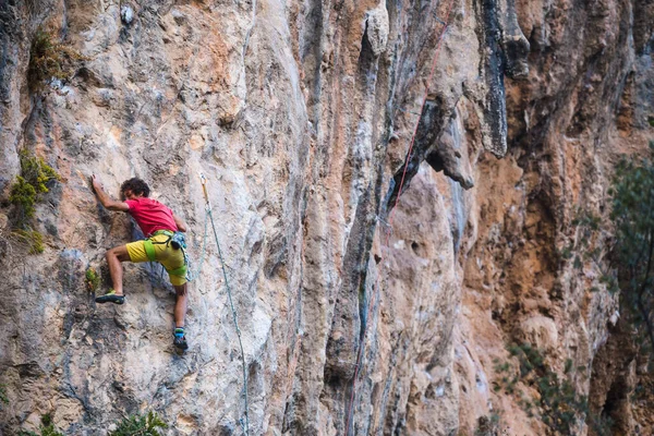 一个强壮的人爬上悬崖 攀登者在自然的地形上克服了一条艰难的攀爬路线 在土耳其攀岩 漂亮的橙色岩石 — 图库照片