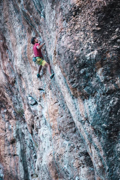 強い男が崖を登る 自然の地形の上で困難な登山ルートを克服します トルコでロッククライミング 美しいオレンジの岩 — ストック写真