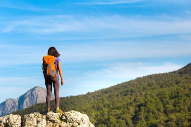 Sırt çantalı bir kadın bir dağın tepesinde durur ve bir dağ vadisinin güzelliğine hayran kalır, güzel yerlere seyahat eder, hedefe ulaşır. Güzel manzara.