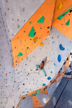 Bir adam tırmanma duvarına tırmanır, bir dağcı yapay arazi eğitimi alır, şehirde kaya tırmanışı yapar, güçlü bir adam, şehirde spor yapar, aşırı sporlarda güvenlidir..