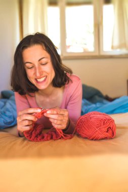Kadın yatakta örgü örüyor, kadın elleri şapka örüyor, karantina sırasında yaratıcılıkla meşgul, el yapımı, favori ev hobisi....