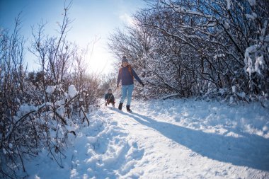 Bir kadın bir çocukla kızak çekiyor, annesi oğluyla karlı bir ormanda yürüyor, parkta kış yürüyüşü yapıyor, çocuk kızakla kayıyor, çocuklarla kış aktiviteleri yapıyor..