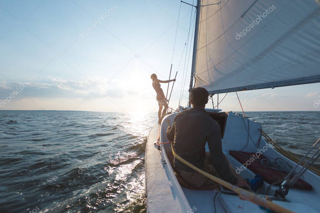 Romantic couple in love on sail boat at sunset under sunlight on yacht, A man and a woman are traveling on a sailing yacht.