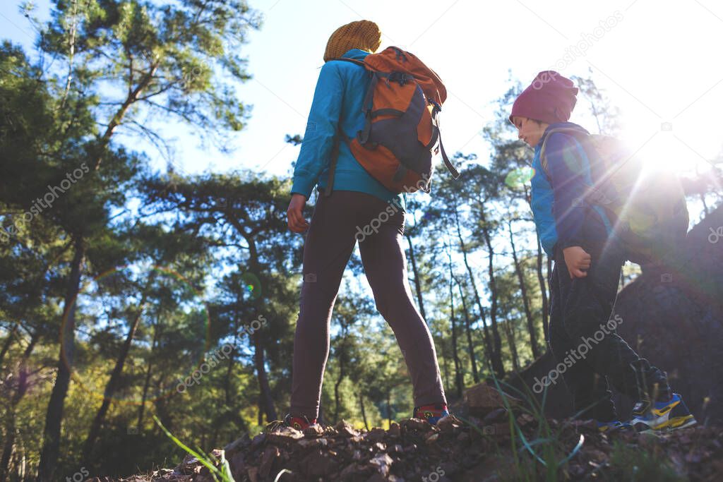 A woman is traveling with a child, Mom and son in the mountains, Climb to the top of the mountain with children, A boy with a backpack walks in the forest with his mother, Active vacations.